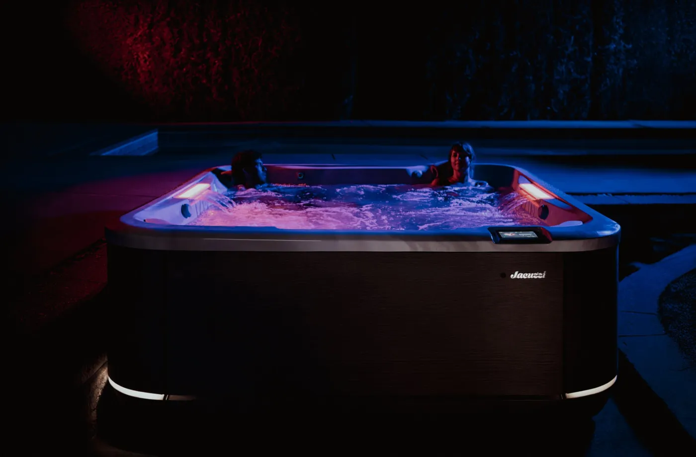 Couple in a Jacuzzi® hot tub at dusk